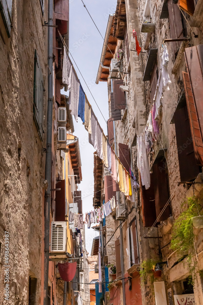 Clean laundry drying between stone houses on a narrow street in the old European city of Rovinj, Croatia
