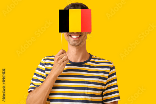 Young man with flag of Belgium on color background photo