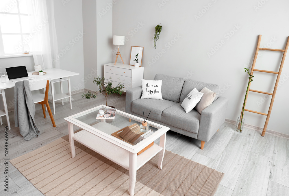 Interior of light living room with coffee table, sofa and workplace