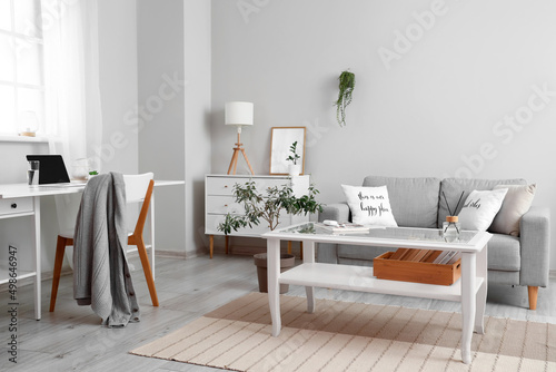 Interior of light living room with coffee table, sofa and workplace © Pixel-Shot