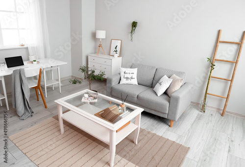 Interior of light living room with coffee table  sofa and workplace