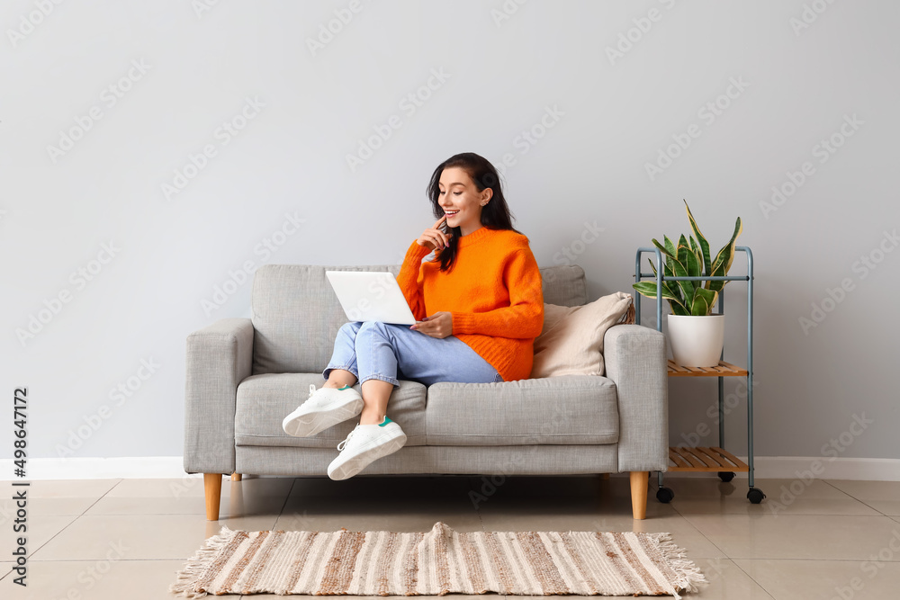 Beautiful young woman with laptop resting on couch at home Stock Photo ...
