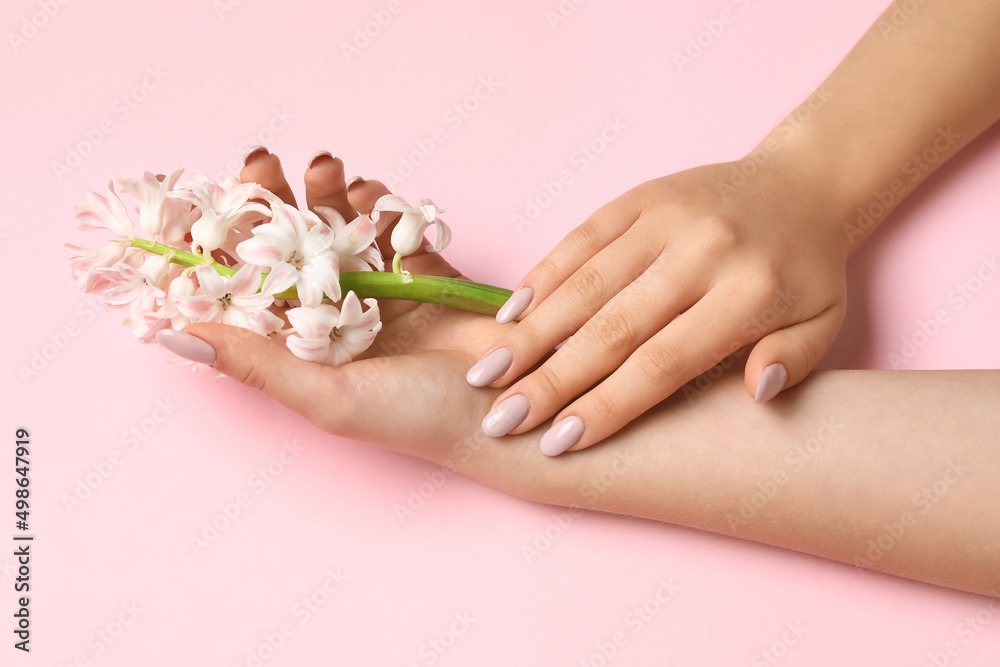 Female hands with beautiful hyacinth flowers on pink background