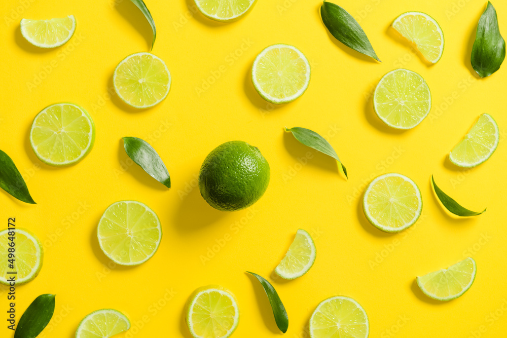 Composition with slices of lime and leaves on yellow background