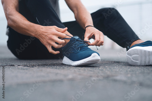 Tie them securely to avoid tripping. Closeup shot of an unrecognisable man tying his laces while exercising outdoors.