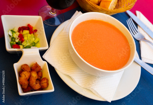 Andalusian traditional cold soup gazpacho in bowl served with vegetables and baked breads