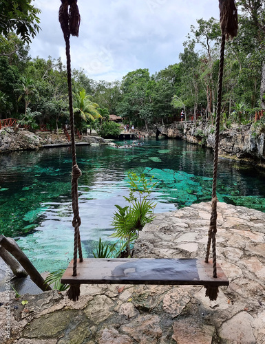 Magical swing in beautiful cenote with turquoise water in Tulum, Mexico. Open underground river