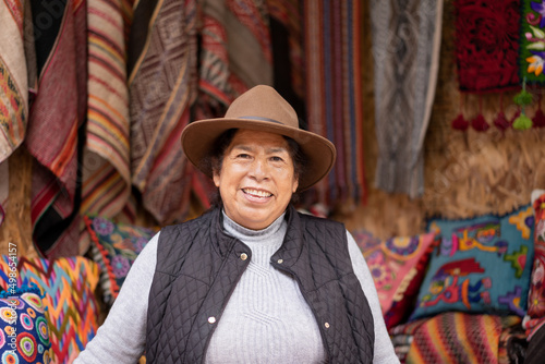 Portrait of a Peruvian woman in an alpaca wool handicraft shop, with ruanas and cushions in the background. photo