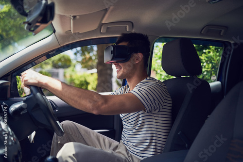 Lets take this new technology for a test drive. Shot of a happy young man driving a car while wearing a virtual reality headset.