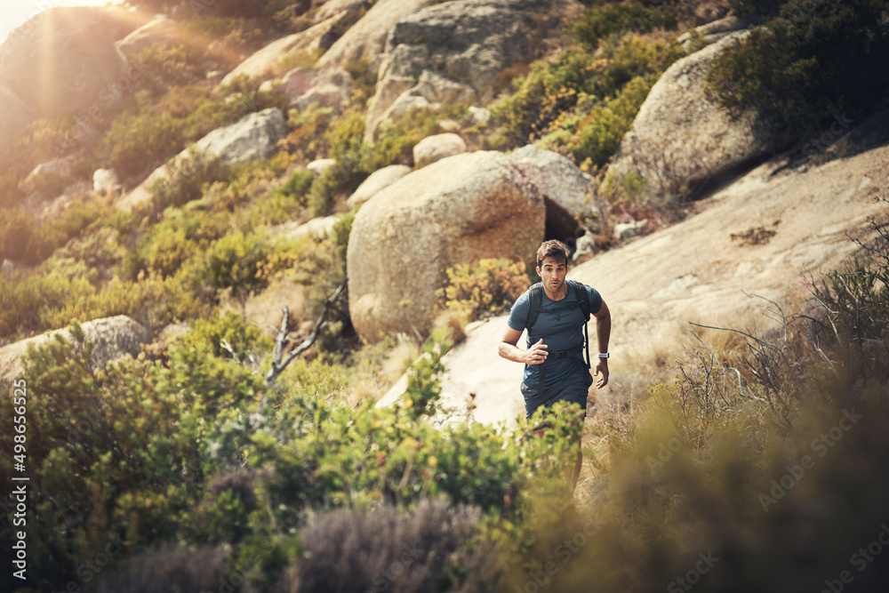Tackling the mountain trail. Cropped shot of a handsome young man running during his hike in the mountains.