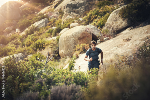 Tackling the mountain trail. Cropped shot of a handsome young man running during his hike in the mountains. © Allistair F/peopleimages.com