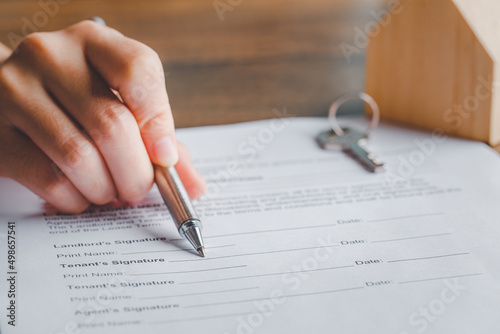 Lease agreement document concept. Realtor or broker showing to signature the tenant's document paper with pen and key, Rental agreement form, signing hand, agreement.