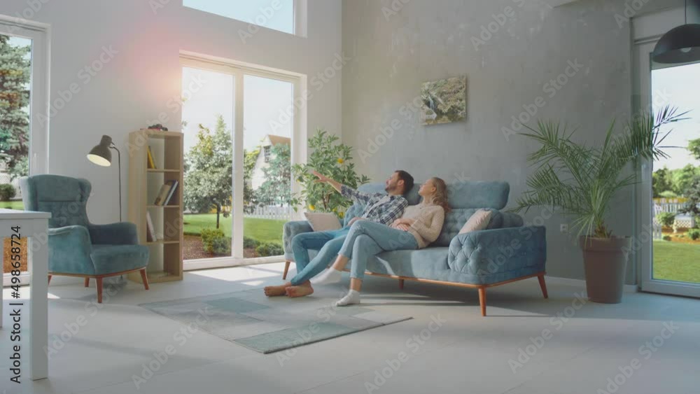 Married couple is relaxing together on the couch and looking outside throughout the window at home