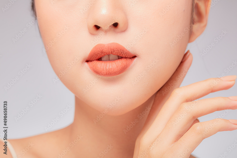 A close view of model showing lip posing with hand for cosmetic advertising