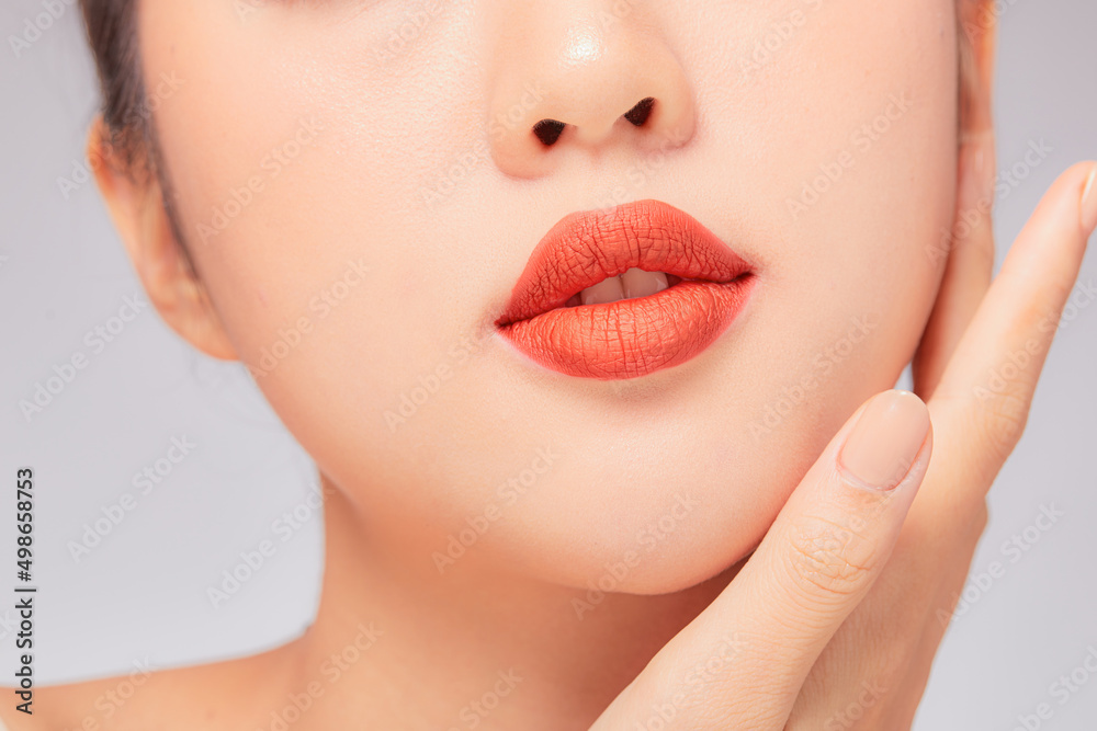 A close view of model showing lip posing with hand for cosmetic advertising