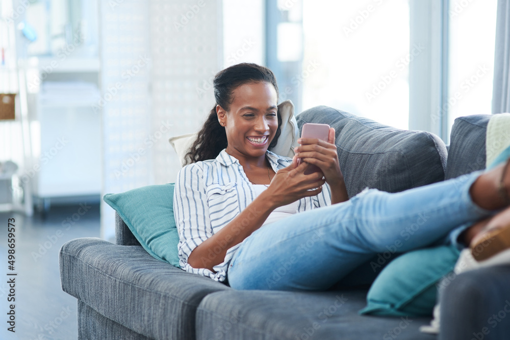 Obraz premium Chatting to her pals. Shot of a young woman texting on a cellphone at home.