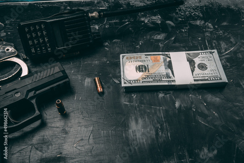 Black pistols, handcuffs, bullets, dollar bills and police radios. Placed on a black wooden table. Corruption police concept. with coppy space photo