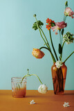 Vertical still life composition on colorful flower bouquet in brown glass vase against light bluish green wall background