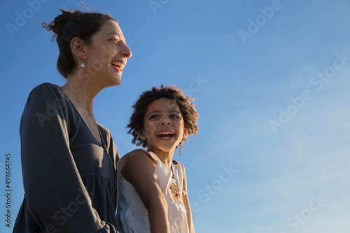 Mother and mixed race adopted daughter having fun together at sunset time outdoors during summer vacation. Love and happiness lifestyle concept. Mother's day.