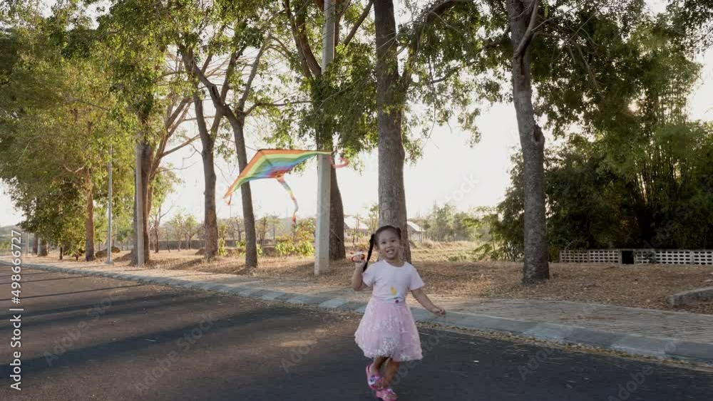 Asian happy children girl with a kite running to fly on in park at summer sunset outdoors