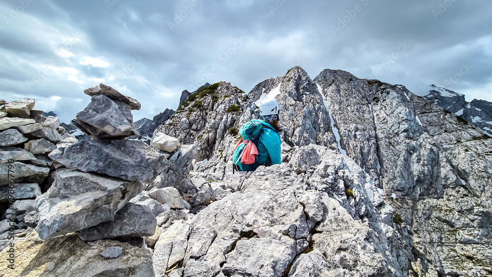 Woman with backpack and helmet hiking on path with scenic view on mountains Kamnik Savinja Alps in Carinthia, border Slovenia Austria. Velika Baba, Vellacher Kotschna. Mountaineering. Freedom concept
