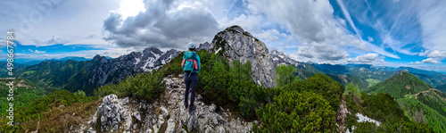 Woman with backpack and helmet hiking on path with scenic view on mountains Kamnik Savinja Alps in Carinthia, border Slovenia Austria. Velika Baba, Vellacher Kotschna. Mountaineering. Freedom concept © Chris