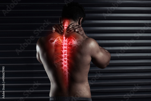 Fototapeta Naklejka Na Ścianę i Meble -  Taking some strain on his back. Rearview shot of an athletic young man holding his back in pain during a workout.