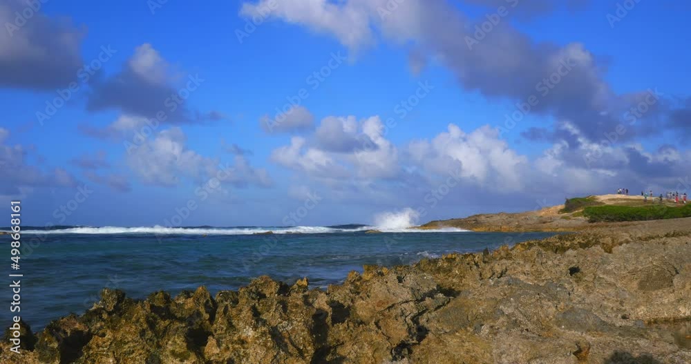 Timelapse of a rocky coastline in the evening druing golden hour. People far in the distance on top of a hill watching the Caribbean sea. Cumulus clouds coming towards. Timelapse of a rocky coastline in the evening druing golden hour. People far in the distance on top of a hill watching the Caribbean sea. Cumulus clouds coming towards.