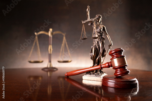 Law and justice concept. War crimes. Gavel, Themis sculpture and scale in lawyers office. Brown background. photo