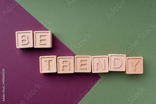 Be trendy. Inscription on a bright background of burgundy and green. Color trends 2022. The text is made up of wooden ecological cubes on a paper background. Fashion and design concept