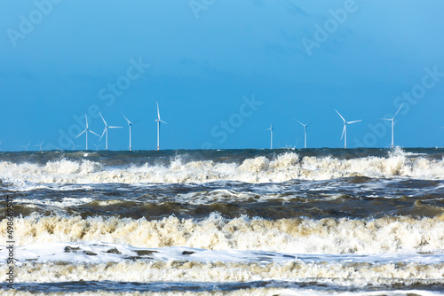 Offshore windmill park in a stormy north sea with spindrift waves photo