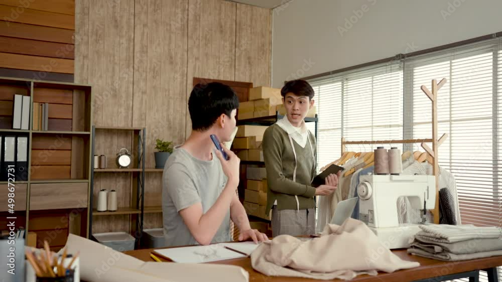4K 50fps, Young LGBTQ Asian Men Small Business Partner,The technician is checking the product according to the order that the customer calls to inquire.Professional Design clothes to sell online.