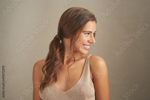 Youll never know just how beautiful you are. Studio shot of an attractive young woman posing against a brown background.