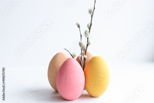 Four colored Easter eggs on a white background, close-up, next to the willow, The concept of the holidays