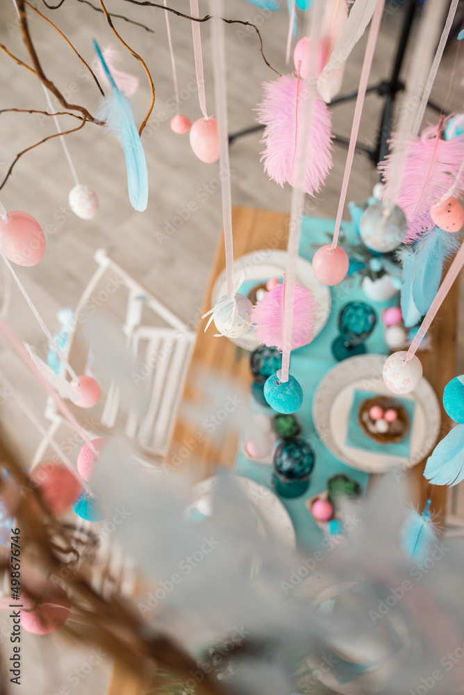 Fototapeta premium Easter pink and blue eggs on served table. Holiday spring composition with nest, glasses and plates