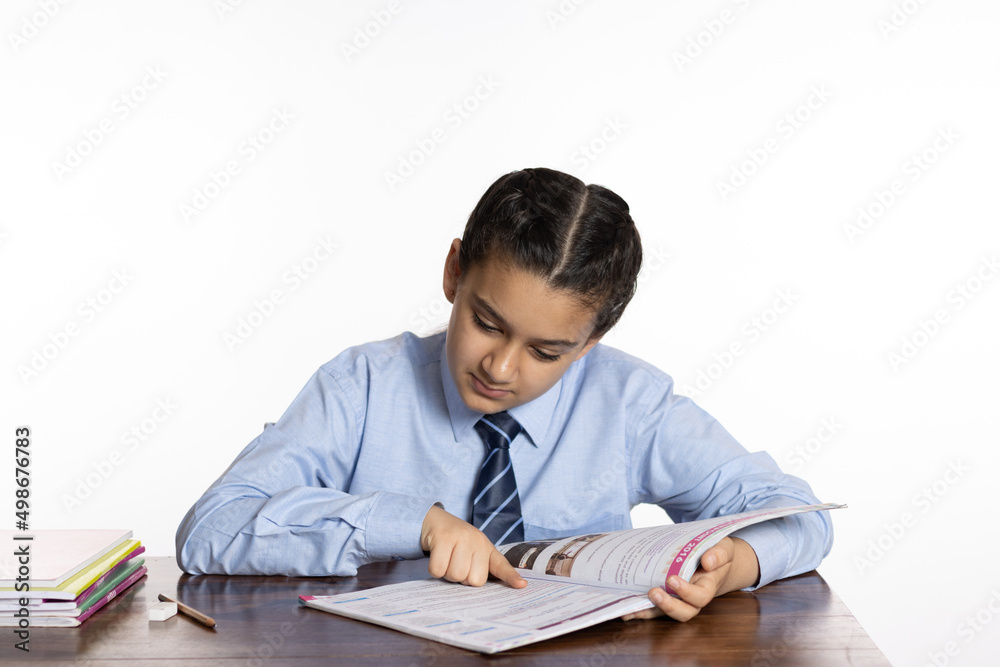 young girl of primary school sitting in classroom reading book isolated on white background young girl of primary school sitting in classroom reading book isolated on white background