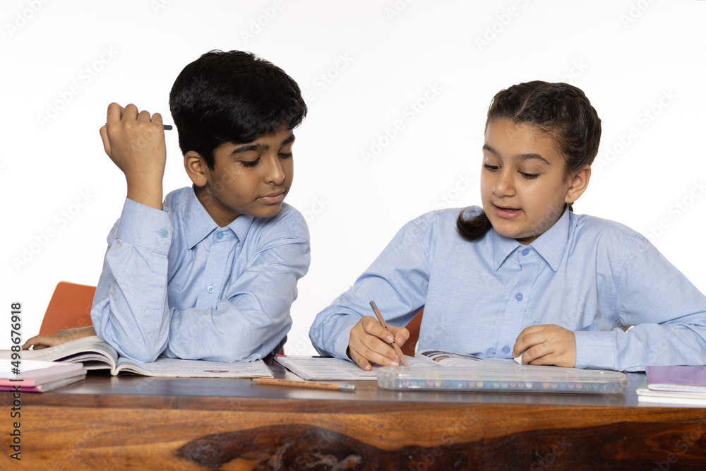 young girl and boy from primary school study in the classroom isolated on the white background