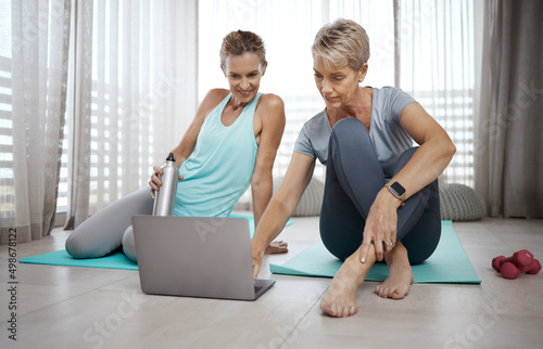 Better sore than sorry. Shot of two mature women browsing the internet for new workout ideas while exercising at home.