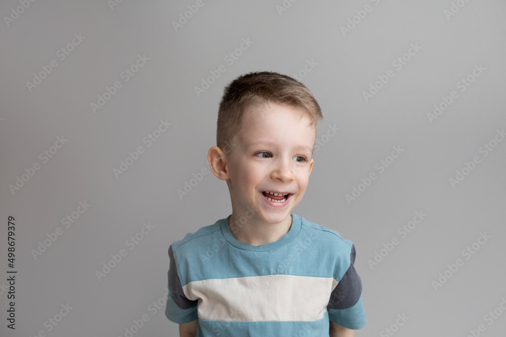 Portrait Cheerful smiling boy 5-8 years old on a gray background