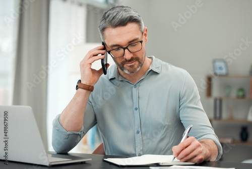 On the phone with his private banker. Cropped shot of a handsome mature man making a phonecall while working on his finances at a desk at home.