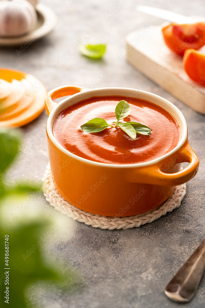 Tomato soup with fresh basil in orange bowl. Bright background. Healthy food concept. Tomato soup with fresh basil in orange bowl. Bright background. Healthy food concept.