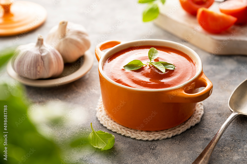 Tomato soup with fresh basil in orange bowl. Bright background. Healthy food concept. Tomato soup with fresh basil in orange bowl. Bright background. Healthy food concept.