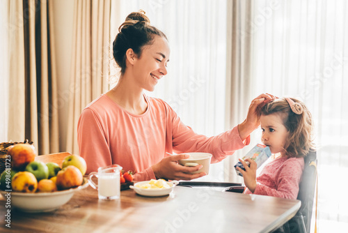 Mother feeding happy toddler girl.