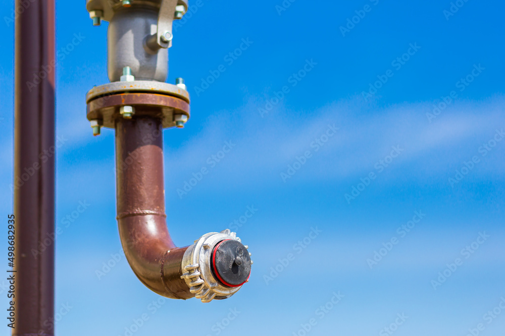 Fototapeta premium Gas pipe with a manual valve close-up against the blue sky