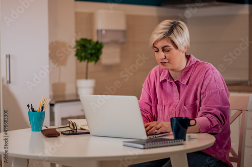 Woman working on a laptop in the kitchen at home