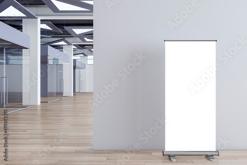 Modern concrete office corridor interior with empty mock up roll up banner on wall, wooden flooring, glass doors with city view reflections. Workplace concept. 3D Rendering.