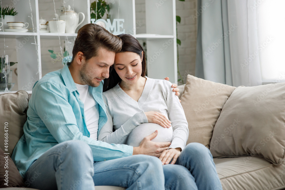 Couple expecting a baby while husband caresses the belly of his pregnant woman..