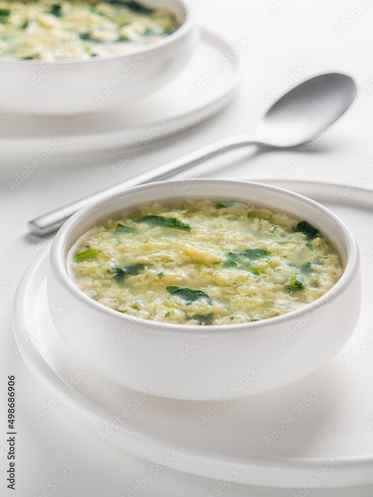 Fresh homemade Italian soup Stracciatella alla Romana with spinach. Egg drop soup. Vertical. Selective focus. High key. Fresh homemade Italian soup Stracciatella alla Romana with spinach. Egg drop soup. Vertical. Selective focus. High key.
