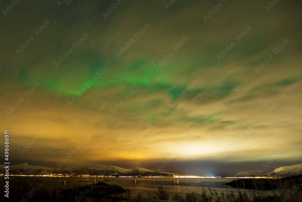 Aurora borealis through the clouds at Blokken in Lofoten Islands. Norway.