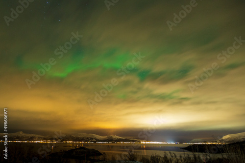 Aurora borealis through the clouds at Blokken in Lofoten Islands. Norway.